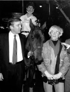 Donald Trump owner of New York's Trump Tower, holds the bridle of a polo pony while talking to Andy Warhol on Nov. 4, 1983. Yale University polo player Eric Stever sits astride the horse. (AP Photo/Mario Suriani)